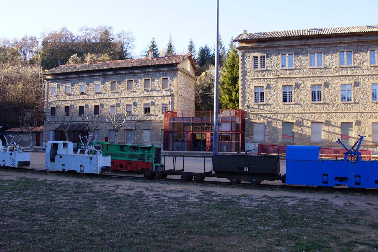 Small mining locomotives and wagons displayed outside the Cercs Mines Museum
