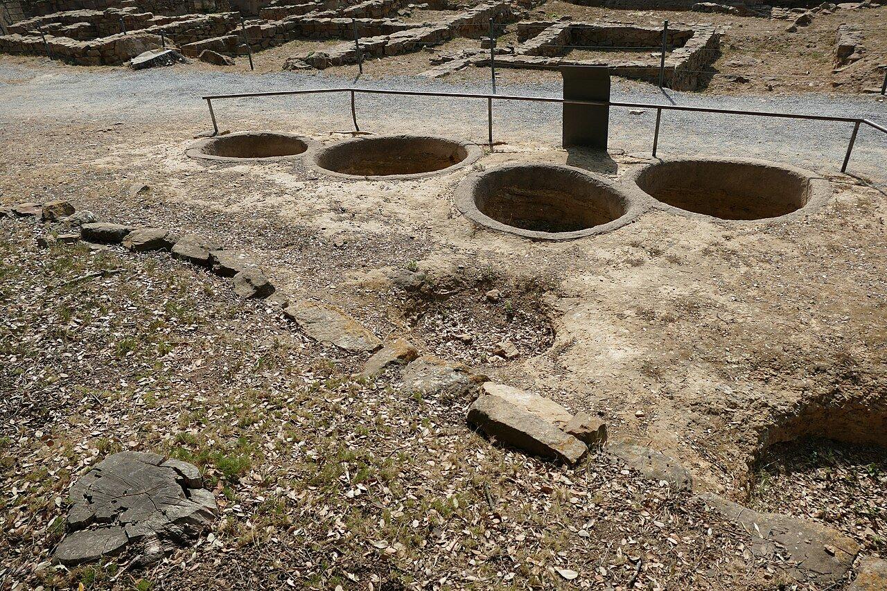 Four circular grain-storage openings behind a railing at Ullastret